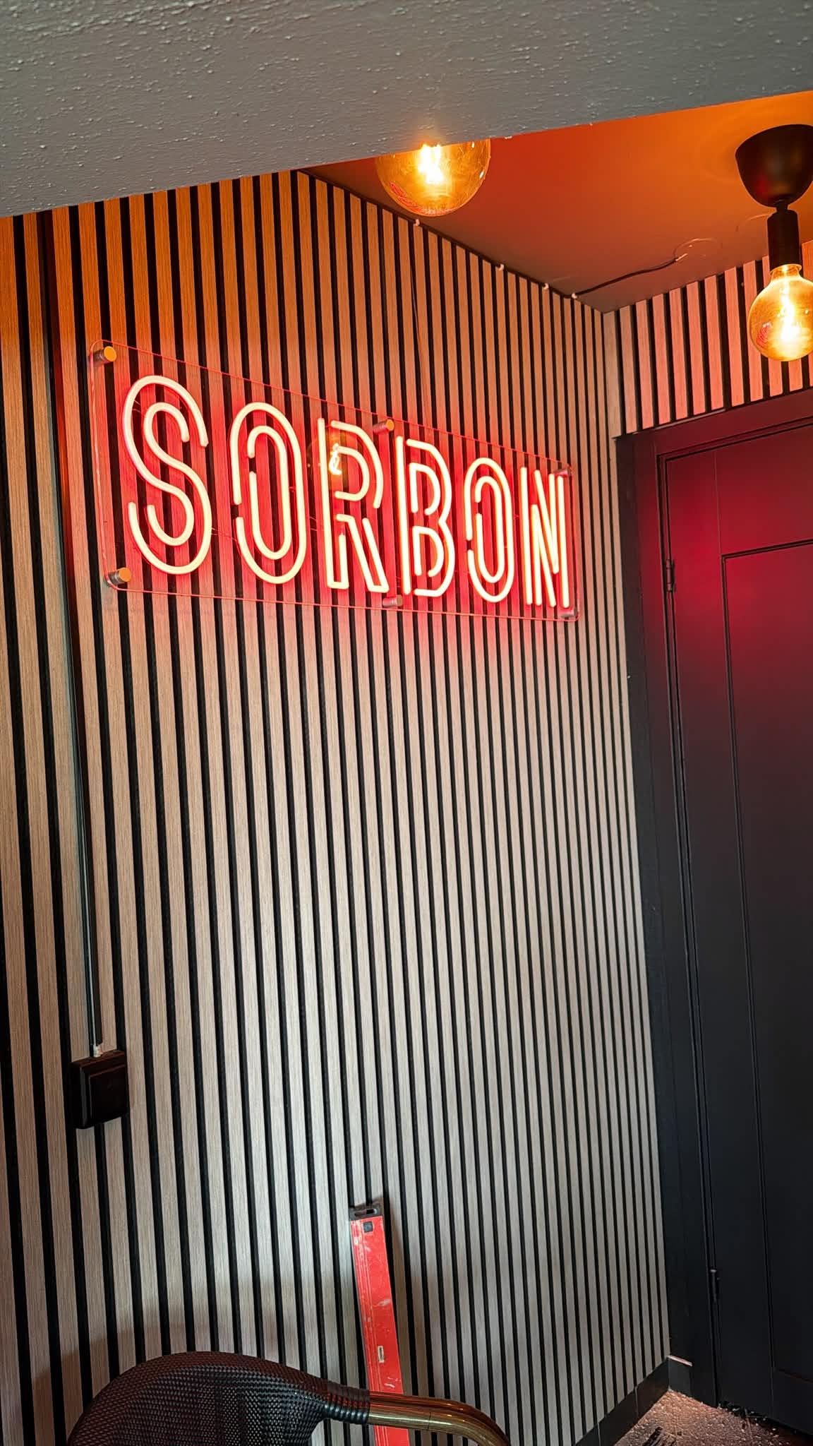 Sorbons neonskylt på panelväggen i restaurangen